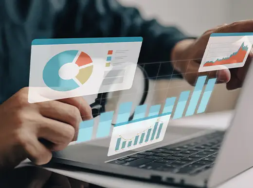 A person uses a laptop with digital screens displaying charts, graphs, and data analytics visuals hovering above the keyboard.