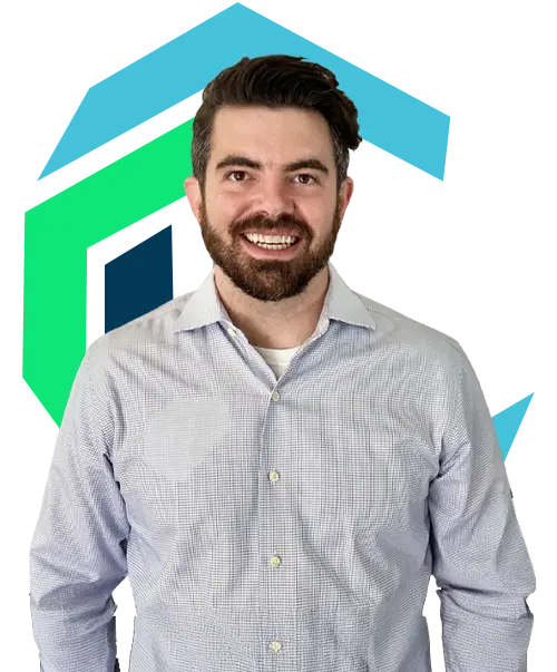 A man with dark hair and a beard, wearing a light plaid button-up shirt, stands smiling in front of a geometric blue and green background.