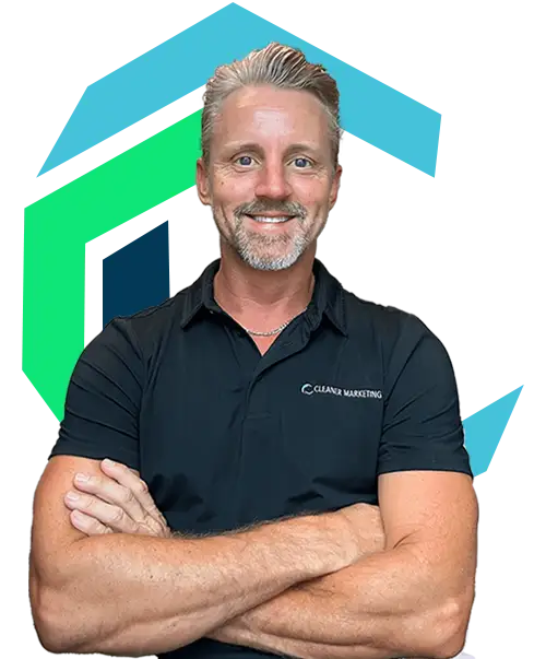 A man with light hair and a beard, wearing a dark polo shirt with folded arms, stands in front of a stylized geometric background.