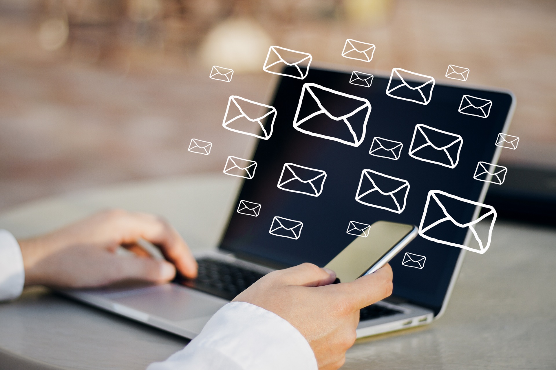 Person using a smartphone and laptop with illustrated email icons floating above the laptop screen, symbolizing digital communication or sending messages.